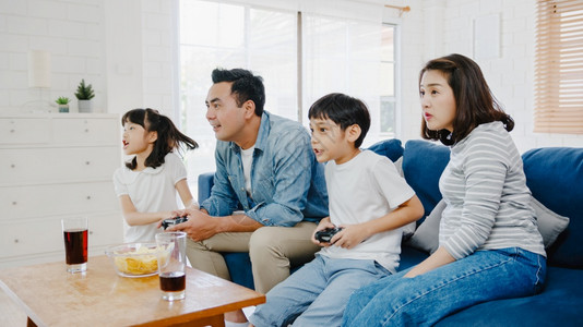 快乐的亚洲家庭爸妈和孩子玩电游戏很有趣在家里的客厅与技术控制台玩游戏自我孤立呆在家中社交不和隔离预防冠状图片