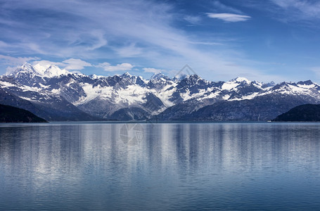 夏季阿拉斯加冰川湾的船离海岸线很近云层和蓝天混合在山脉中图片