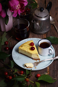 芝士蛋糕在盘子和杯上樱桃一束花附近图片
