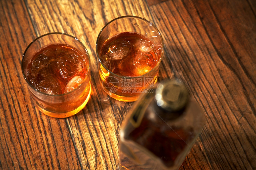 威士忌的两杯酒和木制桌上的一瓶酒图片