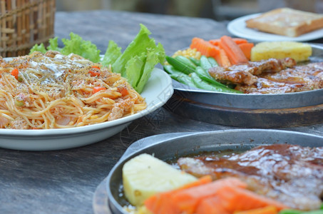 牛肉排猪和意大利面餐桌上的食物图片