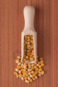在红色黑乙烯基背景下以玉米为背景的木制勺子顶端视图图片