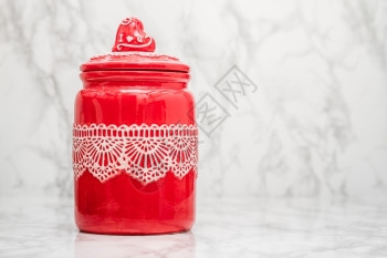 红色圆瓷罐白大理石背景上带花蕾图案图片