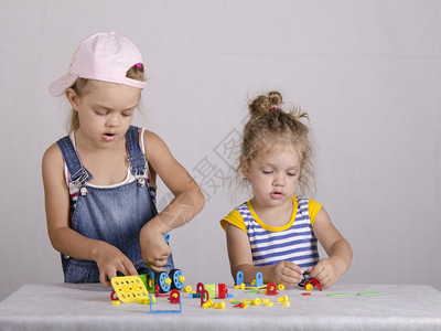 两名女孩在建筑厂里玩耍她们从汽车零件里被收集起来图片