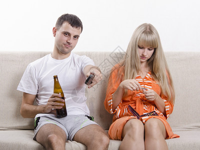 夫妇坐在沙发上他看电视远程开关频道喝啤酒图片