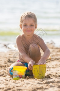 快乐的孩子在沙滩上玩耍带着池塘和沙模图片
