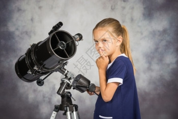 7岁女孩看着天空站在望远镜上图片