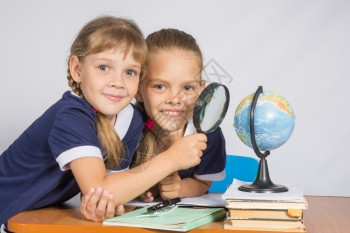 两个女学生通过放大镜目视地球图片