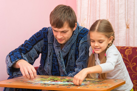 爸爸和女儿在桌子上玩拼图图片