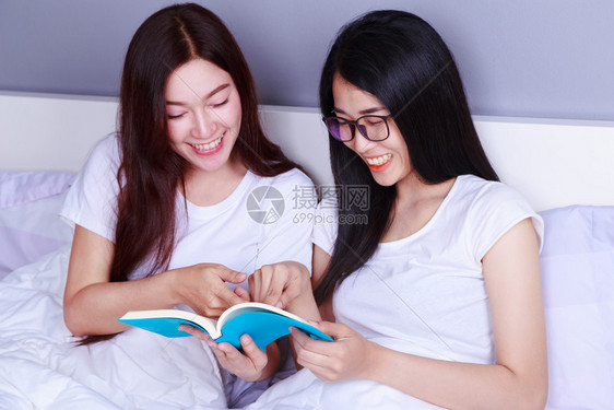 两个女人在卧室的床上看书图片