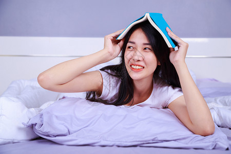 女人在家里卧室的床上看书图片