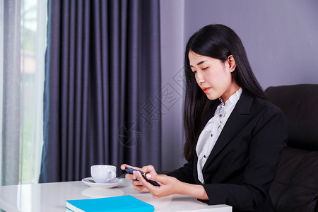 坐在办公桌前并使用移动电话的年轻女商业青图片