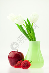 白色的郁金香在花瓶苹果和草莓中与白隔绝图片