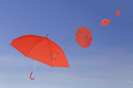 红伞在蓝天背景上被风吹过管理商业念的概图片