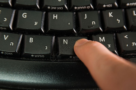 男人在无线键盘上打字用希伯来语和英字母打按下新钮顶级视图图片