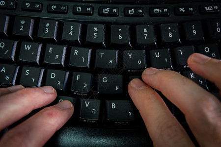 以希伯来语和英字母在键盘上打的人无线键盘顶端视图黑暗气氛图片