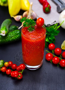 用红番茄和蔬菜做的新鲜果汁在黑色背景的透明杯子里图片