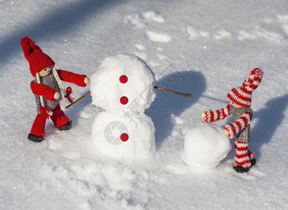 穿红编织衣服的木偶滚雪球在冬天盖人图片