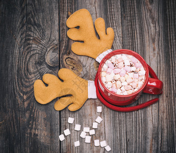 红杯中加棉花糖的热巧克力和棉花糖灰木背景和嘉年华鹿帽图片