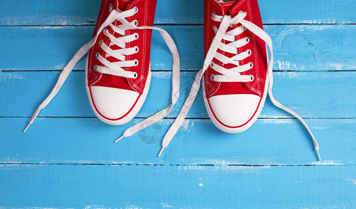 蓝色木背景顶视图空间上白带的一对红色纺织运动鞋图片
