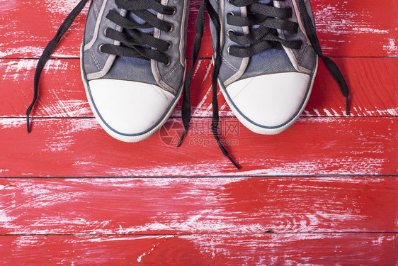 红色木背景的一双旧蓝色纺织品鞋顶部视图图片