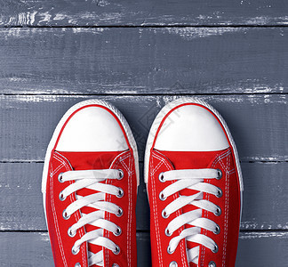 一对红色的纺织运动鞋上面是蓝木背景的白色带子图片