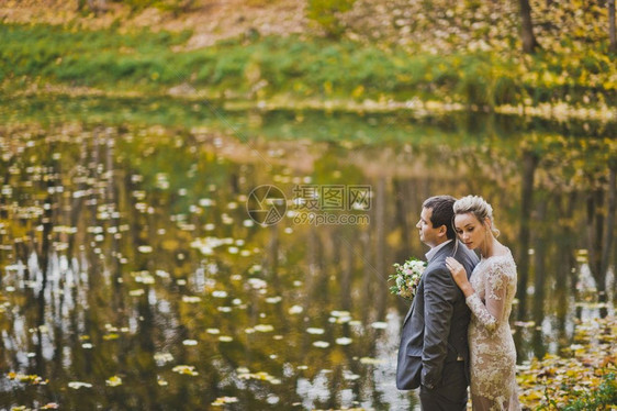 秋天新婚夫妇在森林湖岸边的梦幻肖像图片