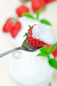 拿勺子挖酸奶和草莓背景图片
