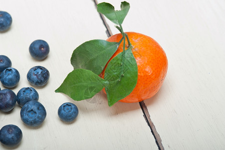 白色锈制木板上的橘子和蓝莓背景图片