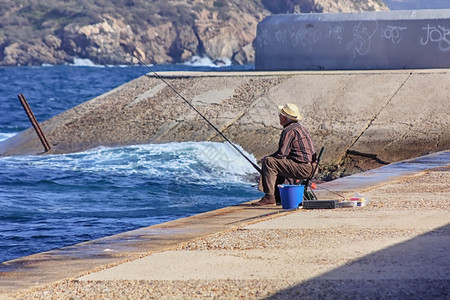 老年男子在海边用拐杖钓鱼图片