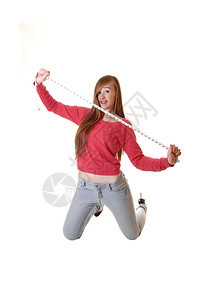 一个十几岁的女孩跪在地上穿着牛仔裤和一件红色毛衣拿着测量胶带长的黑发白本底图片