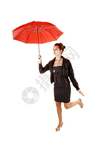 一个穿着黑色裙子棕皮夹克和高跟鞋的可爱年轻女子站在一条腿上白色背景拿着红伞图片