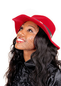 一个可爱的非裔美国女人穿着黑色上衣长的黑色卷发戴着红帽子抬头看着与白色背景隔绝图片