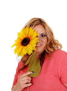 一个穿粉红色毛衣的漂亮女人拿着黄向日葵一眼副肖像微笑与白背景隔绝图片
