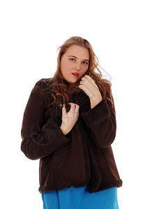 一位美丽的年轻女子站在棕色的冬季夹克与白色背景隔绝看着镜头图片