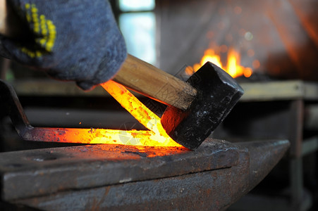 铁匠在铁炉里锻造一个烧红的铁图片