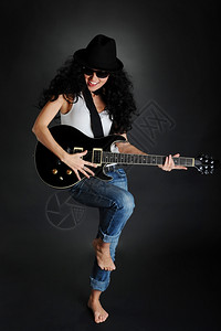 一个美丽的笑女孩肖像手拿着吉他背黑色景图片
