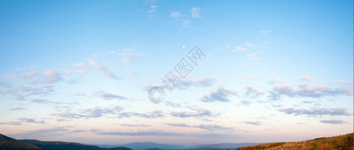 在喀尔巴阡山上方有云和月亮的太阳升起蓝色天空全景两针缝合图象图片