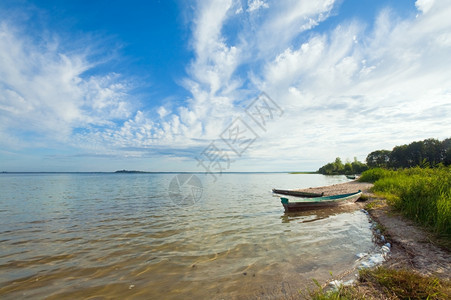 湖岸和后面夏季天空附近的旧木制渔船乌克兰斯维提亚兹图片