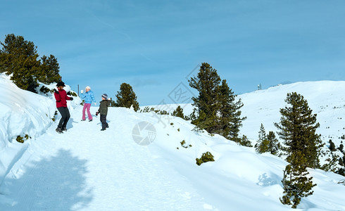 在山坡上滑雪家庭有两个孩子的母亲在冬季山坡上玩雪球游戏背景