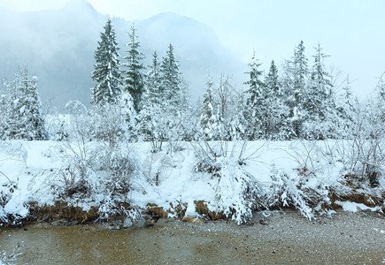 冬天的小溪流河岸上有雪树雾中山上也有雪树图片