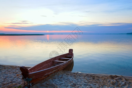 夏季湖岸乌克兰斯维提亚兹附近的日落和老木制渔船背景图片
