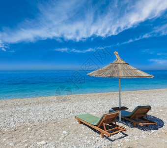 夏晨沙滩有防晒床和草荫的遮阳阿尔巴尼亚深蓝天空有积云背景图片