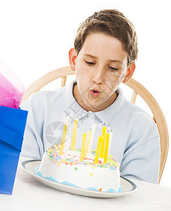 生日男孩吹蜡烛在他的蛋糕上图片