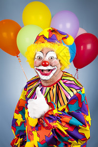 快乐的小丑与气球给拇指举起标志图片