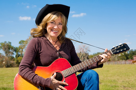 美丽的成熟女牛仔在农场上演奏乡村音乐图片