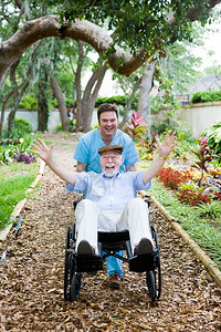 护理家庭员用年长男子的轮椅开着车玩得很开心图片