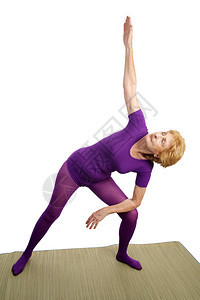 一位70年代的高级女在瑜伽中做三角形变姿势图片