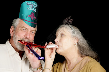 新年派对的一成熟夫妇帽子吹响了噪音制造者图片