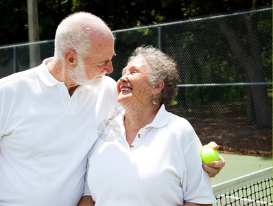 活跃的老年夫妇在网球场上变得浪漫图片